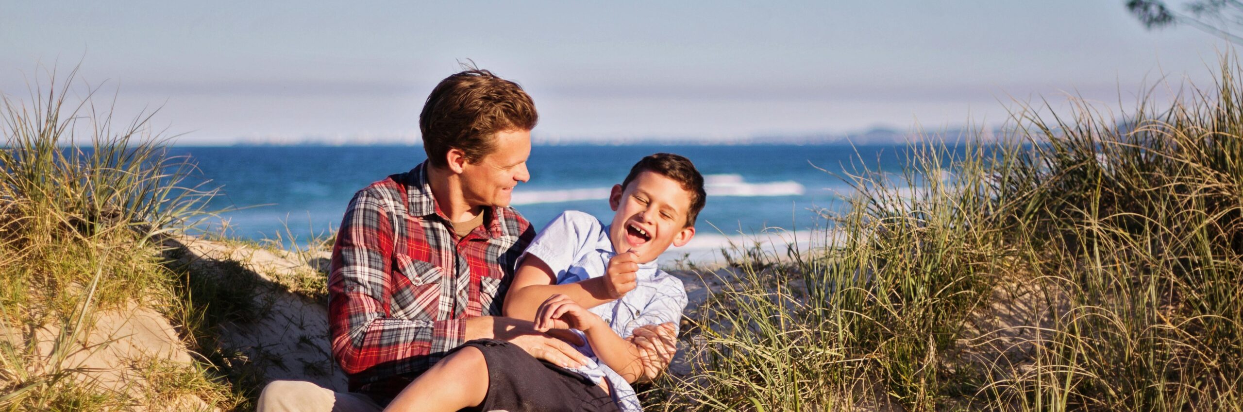 A father and son smiling at the beach